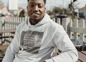 Smiling adult man in a hoodie outdoors, enjoying a sunny day.